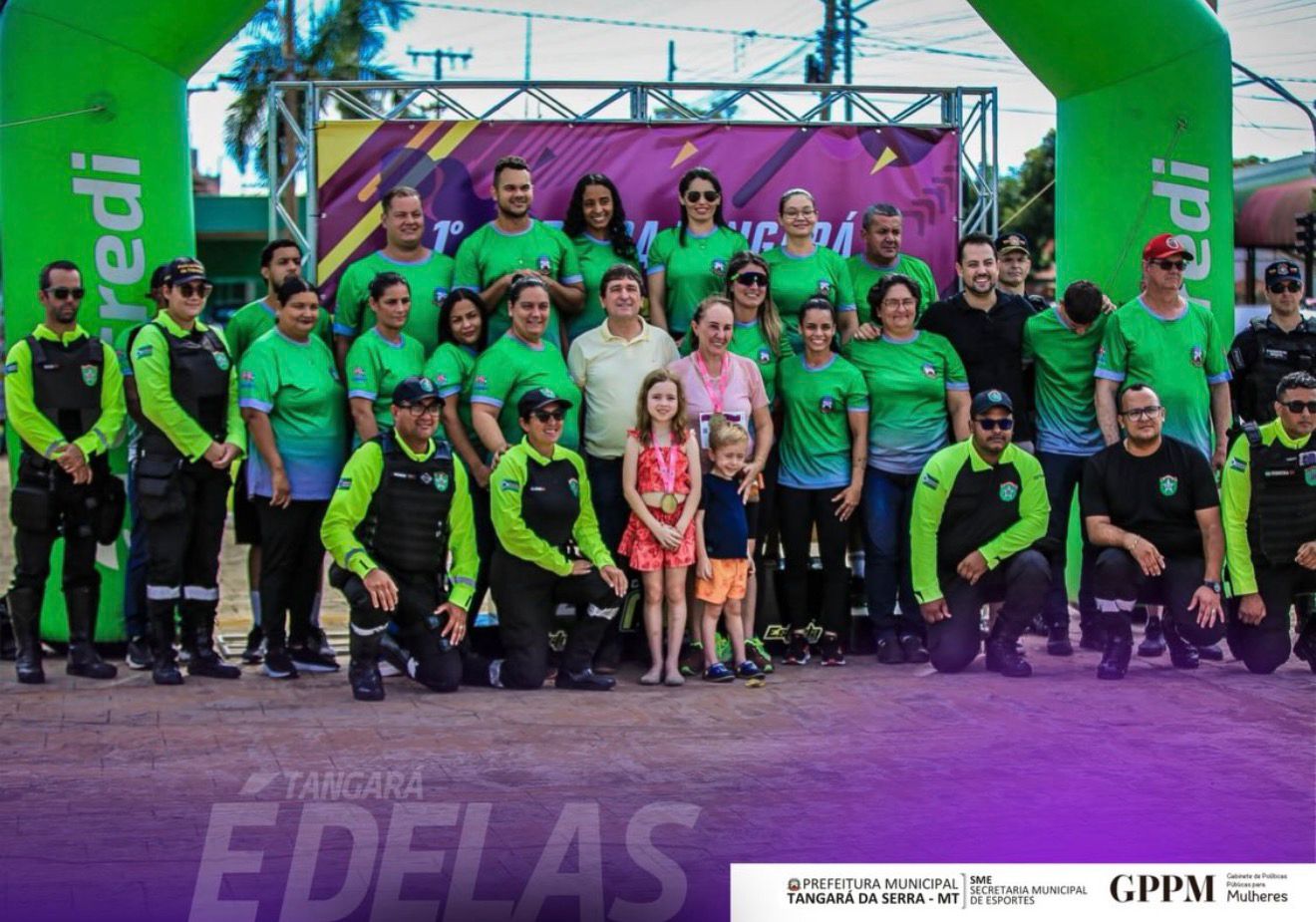 na praça dos pioneiros a foto possui varias mulheres com roupas esportivas após a corrida, policiais fardados, bombeiros e os ajudantes se juntaram na foto também.