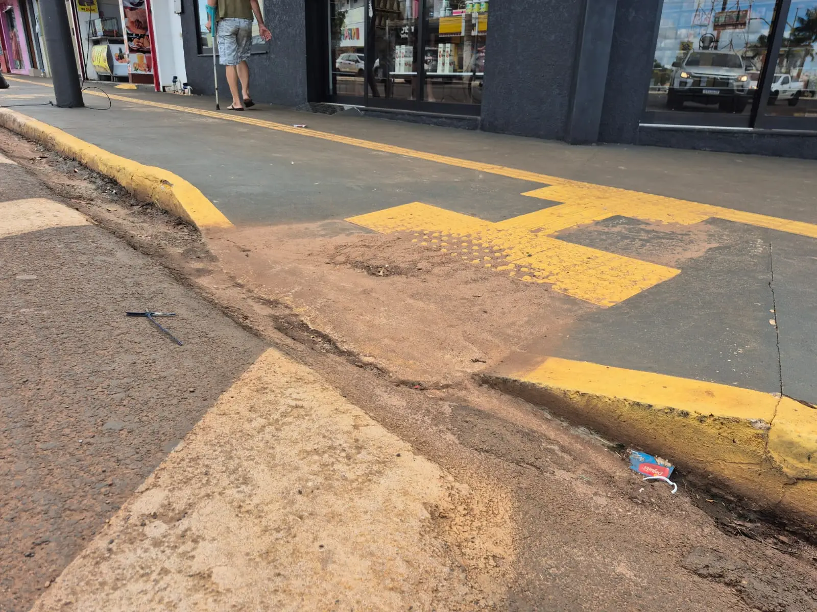 A imagem mostra desnível em uma rampa de acesso no centro da cidade de Tangará da Serra, a rampa esta em bom estado e da acesso a rua da avenida, porém, suja e com muita terra. 